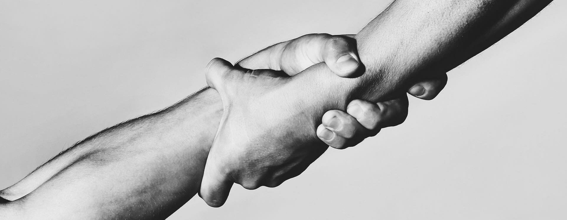 Two hands, helping hand of a friend. Handshake, arms, friendship. Friendly handshake, friends greeting, teamwork, friendship. Rescue, helping gesture or hands. Strong hold. Close-up. Black and white